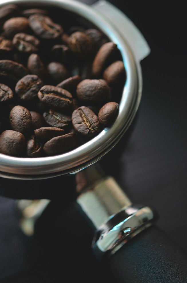 Photo of a silver and black portafilter with Jamaica coffee beans in